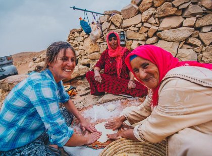 Traveller and local berber woman preparing food at Sahara desert camp, Morocco