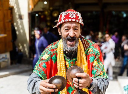 Local man in colourful traditional dress plays music, Fes, Morocco