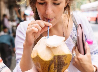 Traveller drinking coconut water from a freshly cut coconut in Mumbai, India on an Intrepid Travel tour.