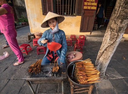 Local woman cooking meat skewers in a pop stall, Hoi An, Vietnam