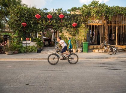 Local boy riding his bike through the streets of Hoi An, Vietnam as seen on an Intrepid Travel tour