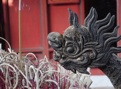 Stone dragon statue head leaning over an incense pit in Hue, Vietnam on an Intrepid Travel tour.