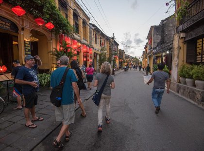 Travellers walking down a twilit street with red lanterns adorning building down the street in Hoi An, Vietnam on an Intrepid Travel tour.