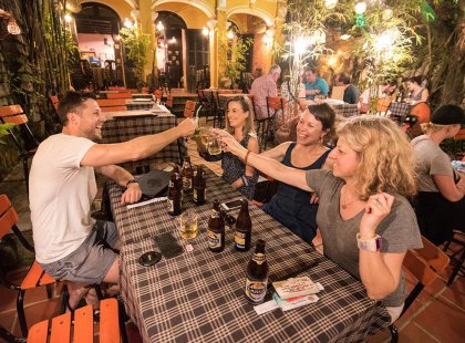 Travellers clinking beer glasses at a restaurant after a big day of sight-seeing in Hoi An, Vietnam on an Intrepid Travel tour.