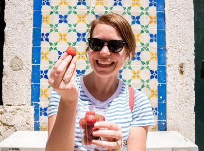 Female traveller with a cup of fresh, ripe strawberries in Lisbon, Portugal on an Intrepid Travel tour.