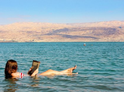 Woman reading book and floating in the Dead Sea, Israel & the Palestinian Territories