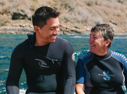 Man and woman smiling in wetsuits, snorkelling in the Galapagos Island