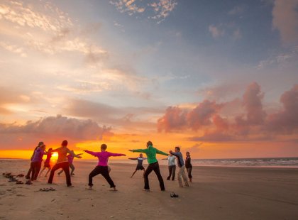 Awaken your senses with sunrise "yoga-inspired" stretching on the beach.