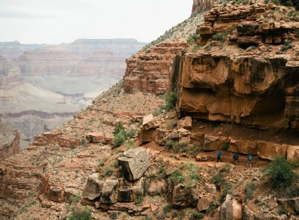Backpackers are dwarfed by immense canyon walls.
