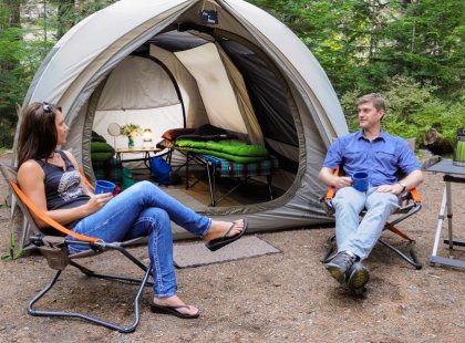 Sleep in oversized tents with cots and comfy REI camp furniture.