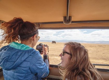 Travellers taking pictures through the jeep viewing roof of an elephant in Ngorongoro National Park, Tanzania on an Intrepid Travel tour