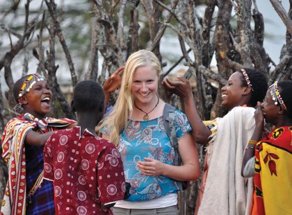 Maasai tribemembers playing with a traveller's blonde hair in Loita Hills, Kenya on an Intrepid Travel tour