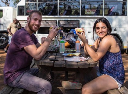 A couple are having lunch in a shady roadside spot during an Intrepid Travel tour in South Africa.