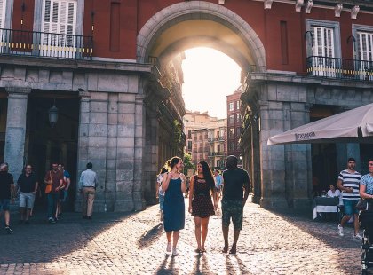 Intrepid travellers walk cobbled city street of Madrid with sunset, Spain