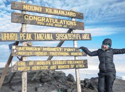 Intrepid traveller at Uhuru Peak summit sign, Mt Kilimanjaro, Tanzania