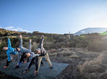 Group of passengers doing yoga at sunset, Mt Kilimanjaro, Tanzania