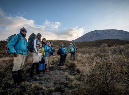 A group of hikers and local guides at sunrise, setting out for the summit of Mt Kiliminjaro, Tanzania