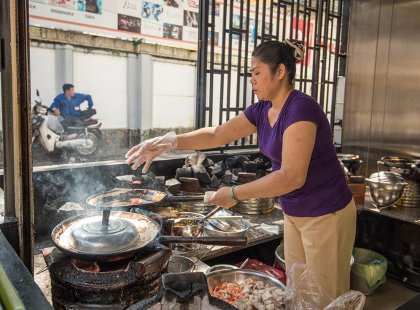 A local cook in a Ho Chi Minh City shopfront cooking a traditonal meal on an Intrepid Travel Tour
