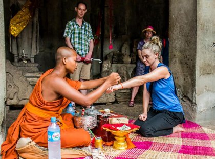 Traveller receiving a blessing wristband from a Buddhist monk in Siem Reap, Cambodia on an Intrepid Travel tour