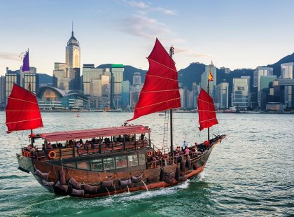 A junkboat sails past the skyline of Hong Kong