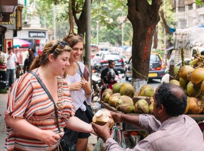 Travellers buying some fresh coconut to drink, India on an Intrepid Travel tour.