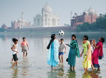 Kids playing football in waters next to Taj Mahal, India