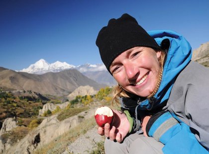 Woman stopping to enjoy an apple on her way up to the Annapurna Ranges in Nepal on an Intrepid Travel tour.