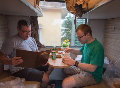 Travellers eating food on board the overnight train between destinations in Vietnam on an Intrepid Travel tour.