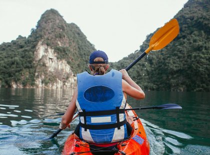 Traveller kayaking around the coast of Nam Cat Island, Vietnam on an Intrepid Travel trip.