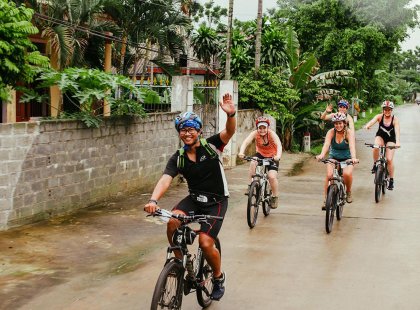 Group leader and other travellers riding through a town on an Intrepid Travel trip in Vietnam.