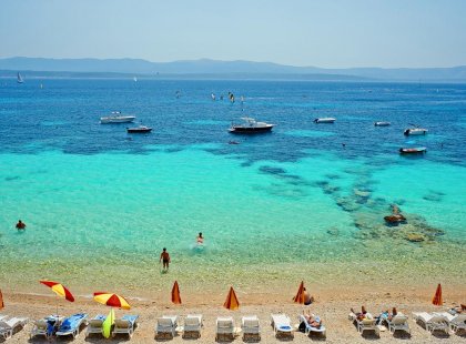 Deck chairs on beach with view of boats and ocean, Brac Island, Croatia