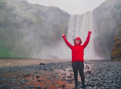 Passenger standing in front of Skogafall waterfalls, Iceland
