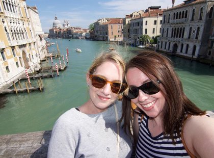 Travellers smiling in a selfie with a Venice cityscape background, Italy on an Intrepid Travel tour.