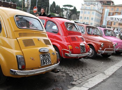 Series of yellow, red, orange and pink Fiat 500 Cars in Rome, Italy.