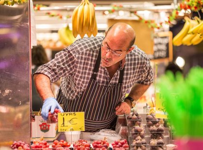 Local vendor sorting and displaying fresh berries on his produce stall in Barcelona, Spain.