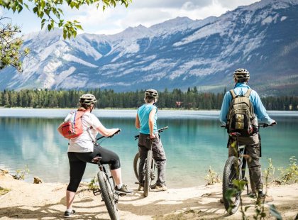 Travellers pausing on their cycling day tour at Edith Lake in Jasper, Canada on an Intrepid Travel tour.