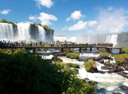 Crowd of tourists on boardwalk beneath scenic Iguazu Falls, border of Argentina and Brazil