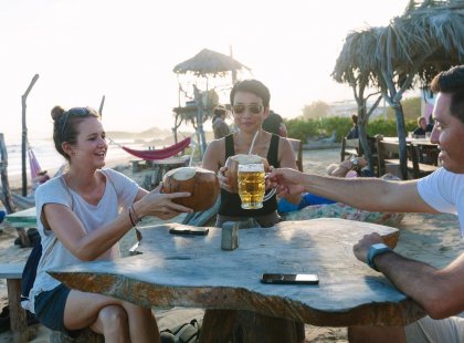Travellers toast drinks on the beach, Galapagos Islands