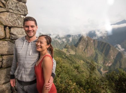 Couple of travellers standing above Machu Picchu, Peru