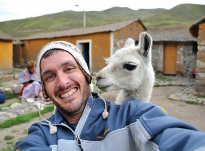 Traveller posing with llama in Peru village